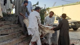 People carry the body of a victim from a mosque following a bombing in Kunduz province