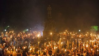 FILE - Demonstrators counter protestors at the base of a statue of Thomas Jefferson after marching through the University of Virginia campus with torches in Charlottesville, Virginia, on Aug. 11, 2017.