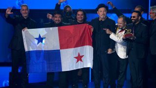 Ruben Blades, Roberto Delgado, and orchestra holding Panama flag