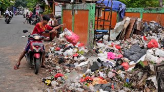 A man throws adds a bag of waste to an open garbage dump in Jakarta, Indonesia, Tuesday, Jan. 25, 2022. Indonesian parliament last week passed the state capital bill into law, giving green light to President Joko Widodo to start a $34 billion construction project this year to move the country's capital from the traffic-clogged, polluted and rapidly sinking Jakarta on the main island of Java to jungle-clad Borneo island amid public skepticism.