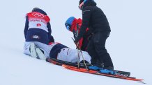 Aaron Blunck, center, of Team United States is helped by medical staff and teammate David Wise, left, after crashing during the Men's Freestyle Skiing Halfpipe Final at the 2022 Winter Olympics, Feb. 19, 2022, in Zhangjiakou, China.