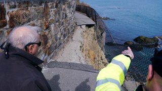 City Manager Joe Nicholson, left, and Public Services Director Bill Riccio review damage along the historic Cliff Walk, Tuesday, March 15, 2022, in Newport, R.I. A roughly 30-foot section of the walk crumbled into the sea last week, leaving officials to ponder whether to rebuild or let if continue to fall into the ocean.