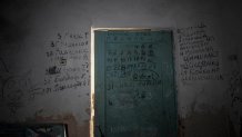 Writing can be seen on a wall and a door in the basement of a school in Yahidne, near Chernihiv