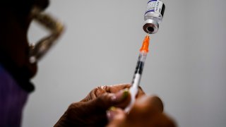A syringe is prepared with the Pfizer COVID-19 vaccine at a vaccination clinic