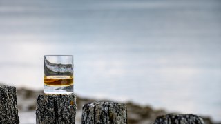 A file image of a glass of whiskey in front of the ocean
