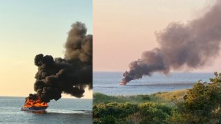 A boat goes up in flames off Corporation Beach in Dennis, Massachusetts, on Wednesday, July 20, 2022.