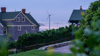 This July 14, 2021, file photo shows a wind turbine between two homes in Hull, Massachusetts.