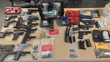 guns and pieces of guns out on a table as evidence in a police investigation