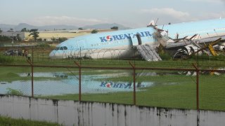 A damaged Korean Air plane sits after it overshot the runway