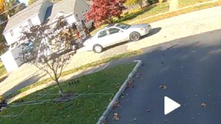 a tan sedan drives down a suburban street