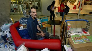 FILE - Merhan Karimi Nasseri sits among his belongings at Terminal 1 of Roissy Charles De Gaulle Airport