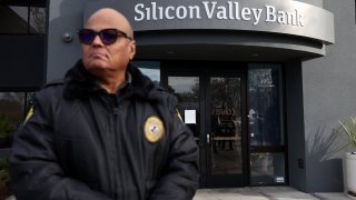 A security guard at Silicon Valley Bank monitors a line of people outside the office on March 13, 2023 in Santa Clara, California.