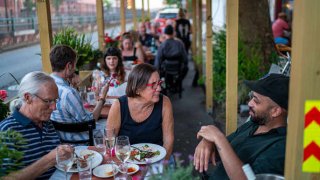 People sit outdoors at the Petite Crevette Restaurant on June 05, 2021 in the Brooklyn borough of New York City.