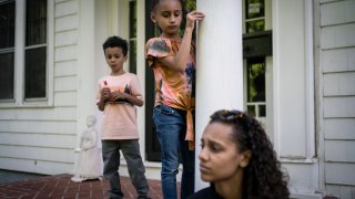 Catherine Manson sits on the front porch of her aunt's home as her children, Caydence Manson, center, and Carter Manson, play close by in Hartford, Connecticut, May 25, 2022. About 4 million children in the United States, including Caydence and Carter, currently have asthma. But stark disparities exist: More than 12% of Black children nationwide suffer from the disease, compared with 5% of white children.