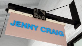 A Jenny Craig sign hangs on the wall outside of the weight loss store
