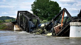 Several train cars are immersed in the Yellowstone River after a bridge collapse near Columbus, Mont., on Saturday, June 24, 2023.