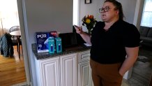 Colleen Colarusso, shows a water purification carafe and filters received from Providence Water after being alerted of health concerns from her residential water delivered through lead pipes, in the kitchen of her home, Thursday, March 23, 2023, in Providence, R.I. Testing showed lead levels in her water at more than twice the federal limit. Before that, she drank and cooked with tap water. (AP Photo/Charles Krupa)