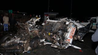 People stand near the wreckage of vehicles after a fatal accident in Londiani, Kenya