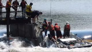 A still from a video showing people being rescued from a boat stuck on a dam on a fast-flowing river in Lebanon, New Hampshire, on Wednesday, July 12, 2023.