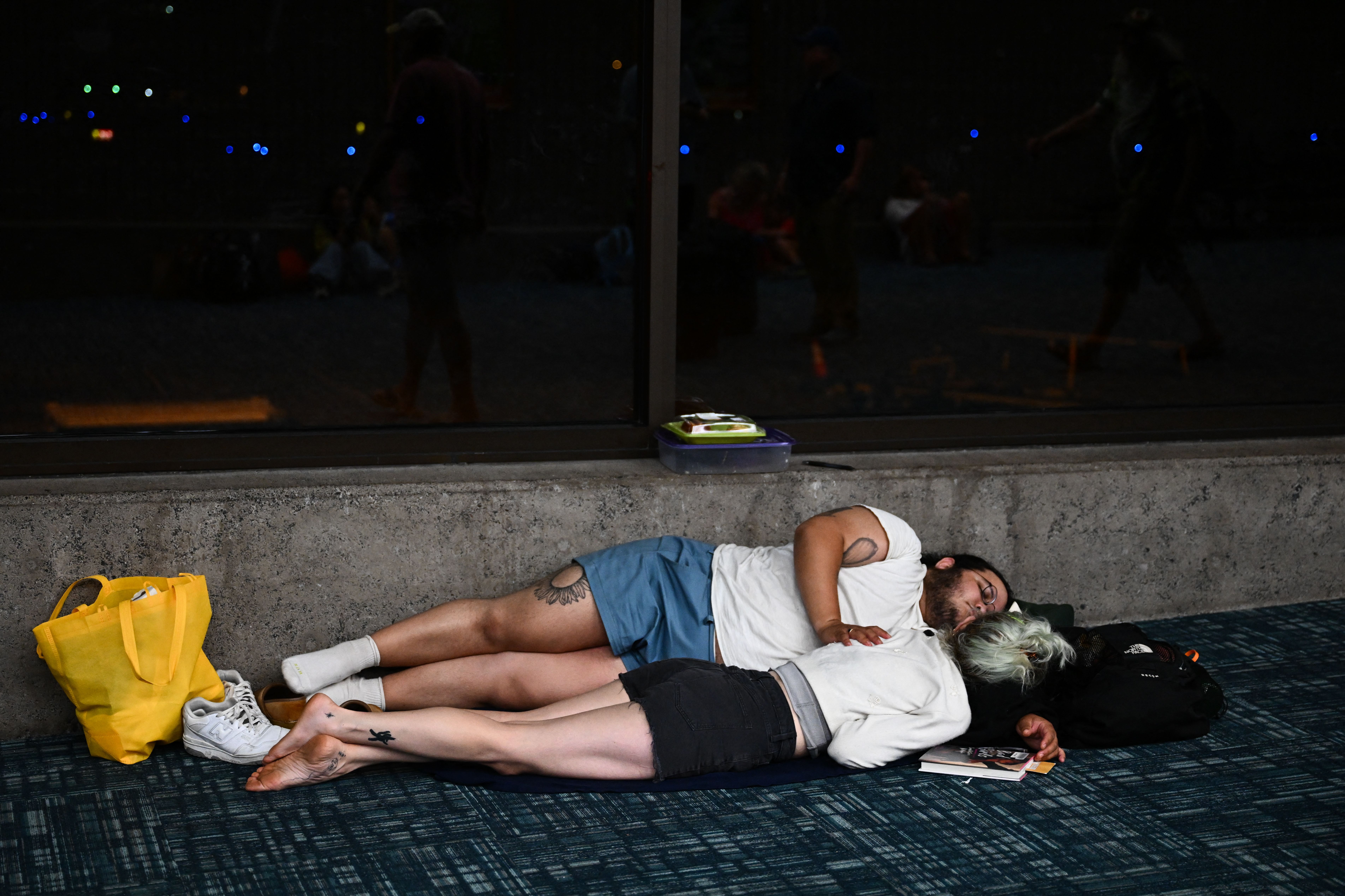 Passengers try to rest and sleep after canceled and delayed flights while others wait to board flights off the island as thousands of passengers were stranded at the Kahului Airport in the aftermath of wildfires in Maui in Kahului, Hawaii, Aug. 9, 2023.