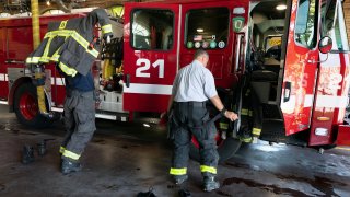 Firefighter Rod MacKinnon, left, and Lt. Chris Stevens don their turnout gear as they respond to a call at the Engine 21 fire station, Thursday, Aug. 24, 2023, in the Dorchester neighborhood of Boston.