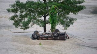 A vehicle that got washed away lies beneath a tree after flash floods triggered by a sudden heavy rainfall swamped the Rangpo town in Sikkim, India, Thursday, Oct.5. 2023.