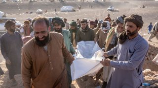 Afghan people carry the body of a relative killed in an earthquake at a burial site after an earthquake in Zenda Jan district in Herat province, western of Afghanistan, Monday, Oct. 9, 2023.