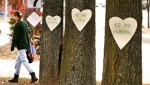 Artist Miia Zellner walks away after nailing hearts she made to trees on Main Street in Lewiston, Maine, the day after mass shootings took place in the city.