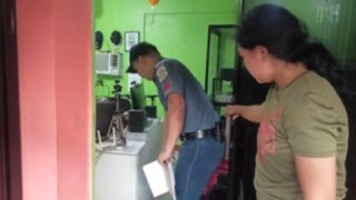 In this handout photo provided by the Calamba Municipal Police Station, a policeman, left, checks on the area where a radio anchor was fatally shot by a man inside his home-based station in Calamba town in Misamis Occidenta province, southern Philippines on Sunday Nov. 5, 2023.