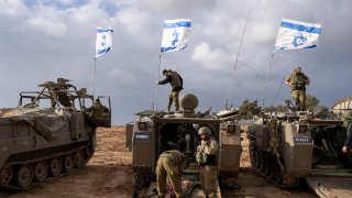 Israeli soldiers work on armored military vehicles along Israel's border with the Gaza Strip