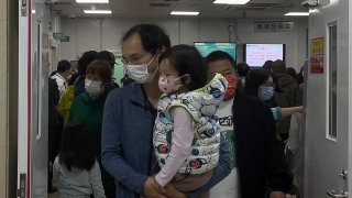 A man carriers a child walk out from a crowded holding room of a children's hospital in Beijing