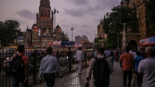 Pedestrians walk towards the Chhatrapati Shivaji Terminus train station at dusk in Mumbai, India, on Wednesday, Oct. 4, 2023.