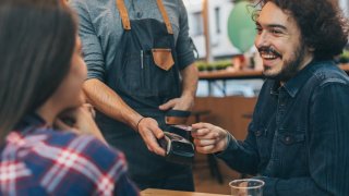 Boyfriend pays the bill at the cafe via credit card.