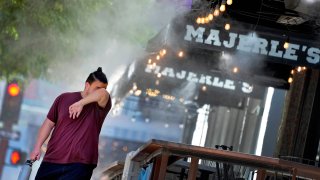 File photo: A man wipes his brow as he walks under misters on Thursday, July 13, 2023 in downtown Phoenix.