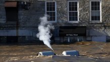 Propane tanks set free by flood waters discharge gas as they float on the Kennebec River.