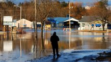 A man pauses at the edge of a flooded road near the Kennebec River.
