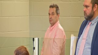 Steve Docchio, wearing a pink shirt, stands in court