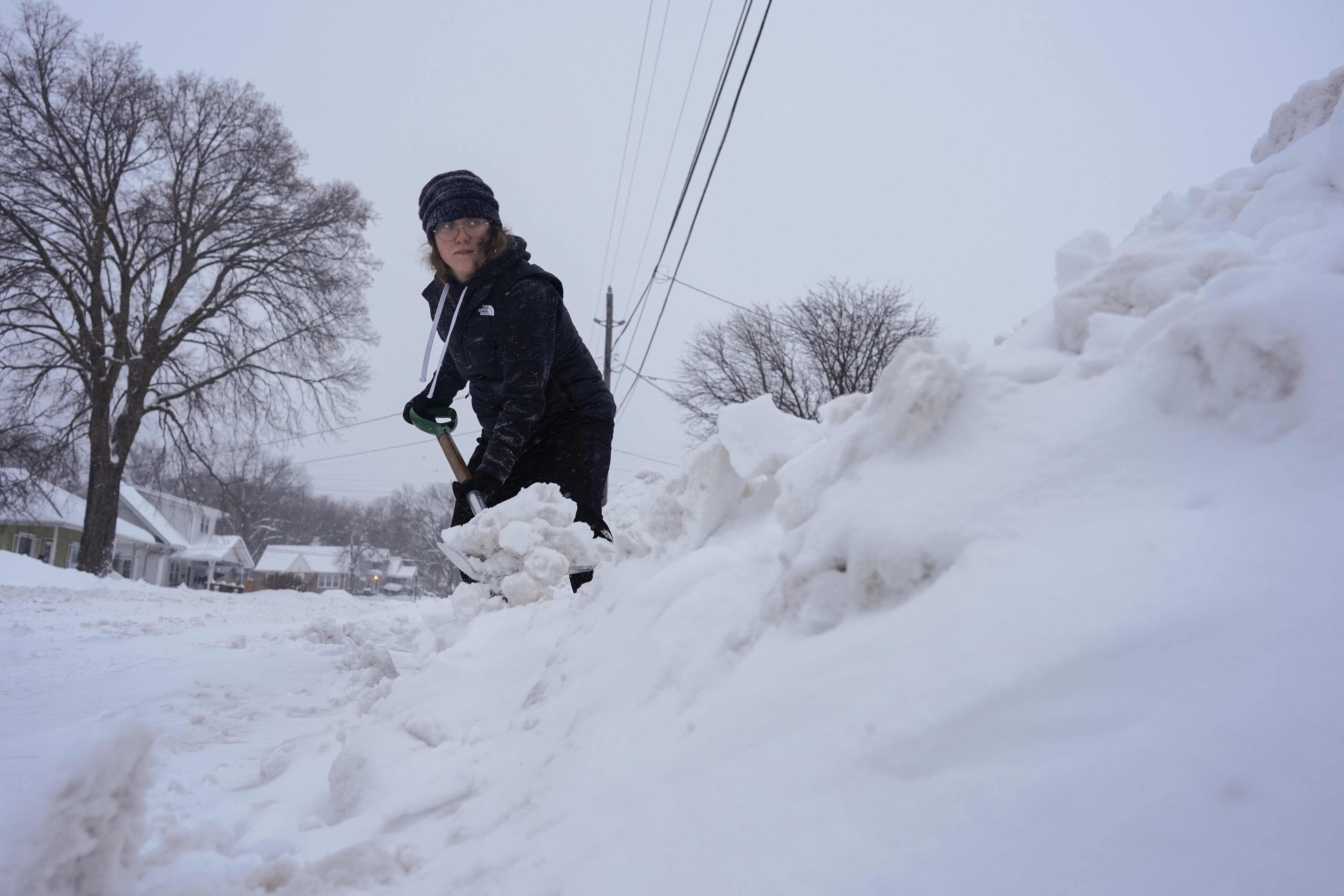 Graphic designer Emily Brewer shovels out her driveway in order to drive to work in Sioux City, Iowa, early on Friday, Jan. 12, 2024.