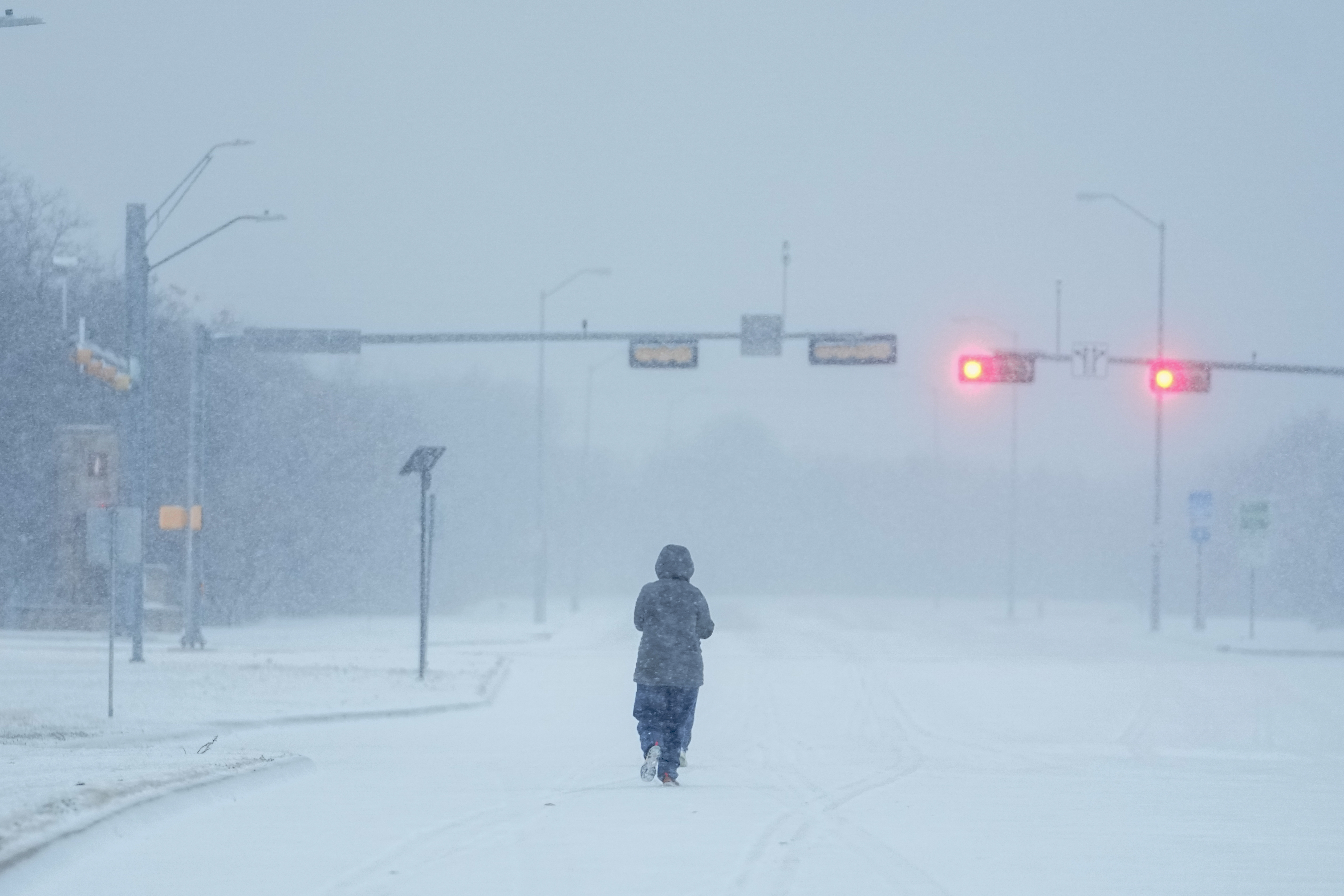 A jogger trots on a snow-covered road during a winter storm, Monday, Jan. 15, 2024, in Grand Prairie, Texas.