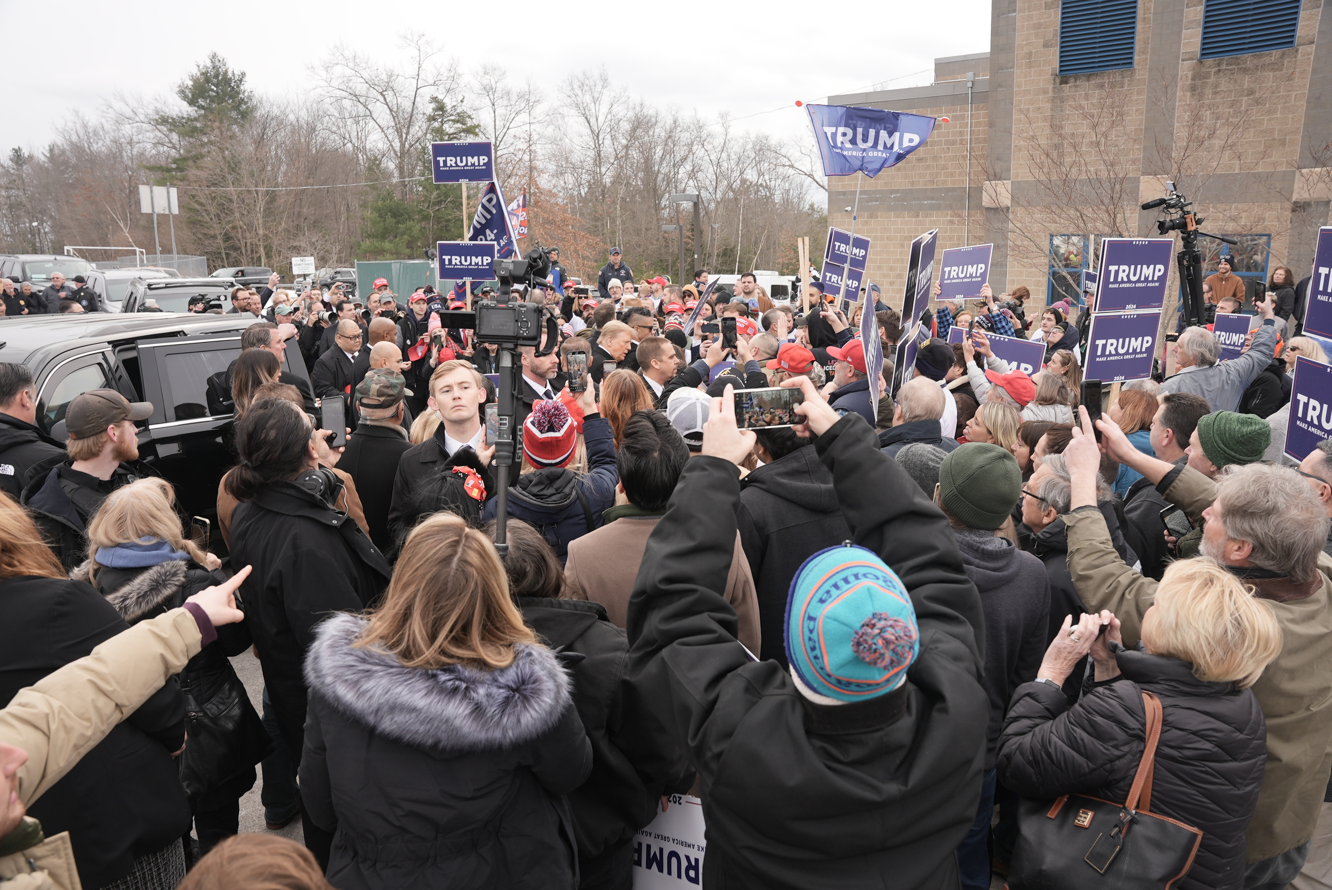 A crowd gathers around former President Donald Trump as he arrives at a polling location in Londonderry, New Hampshire on Tuesday, Jan. 23, 2024.