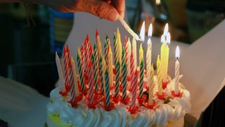 A person lights birthday candles on a cake.