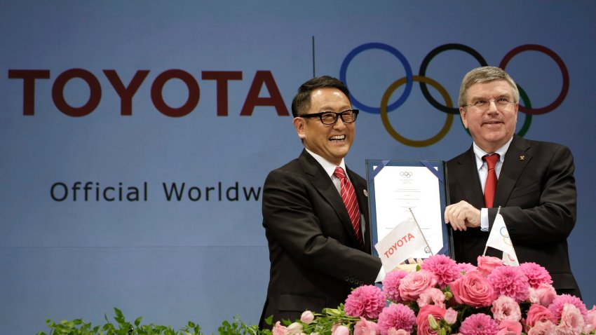 FILE – Toyota President and CEO Akio Toyoda, left, and IOC President Thomas Bach pose with a signed document during a press conference in Tokyo, on March 13, 2015 as Toyota signed on as a worldwide Olympic sponsor in a landmark deal, becoming the first car company to join the IOC’s top-tier marketing program.