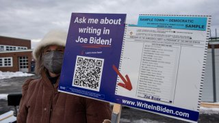 A supporter of US President Joe Biden holds a sign outside a polling site during the state’s primary at Winnacunnet High School in Hampton, New Hampshire on January 23, 2024. Former US President Donald Trump aims to steamroll his way toward the Republican presidential nomination Tuesday in the New Hampshire primary, making short work of his only surviving opponent Haley. (Photo by Joseph Prezioso / AFP) (Photo by JOSEPH PREZIOSO/AFP via Getty Images)