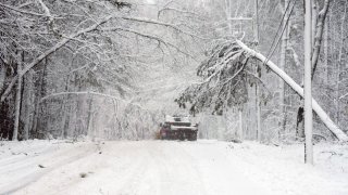 KENNEBUNK, ME – APRIL 4: A truck navigates through trees weighted with snow on Wichers Mill Road in Kennebunk on Thursday. A nor’easter is dumping heavy, wet snow which, combined with strong winds, are causing trees and limbs to fall resulting in another round of power outages in the region. (Staff photo by Gregory Rec/Portland Press Herald via Getty Images)