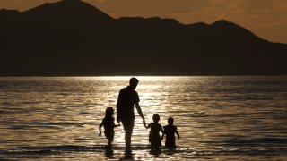 A family walks in the water during sunset at the Great Salt Lake Thursday June 13, 2024, near Salt Lake City.