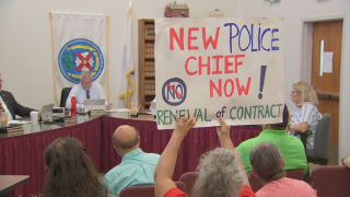 A protester holds up a sign reading "New police chief now!" at the Canton Select Board meeting on Tuesday, June 25, 2024.