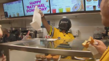 A Savannah Banana player in helmet handing out donuts at Dunkin' in Kenmore Square.