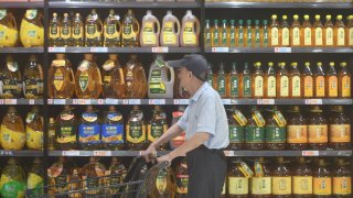 A shopper passing by shelves of cooking oil in a supermarket in Hangzhou city in China’s Zhejiang province.