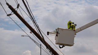 A CenterPoint foreign assistance crew worker wipes sweat from his brow as he works with others to restore power lines on July 11, 2024 in Houston, Texas. 