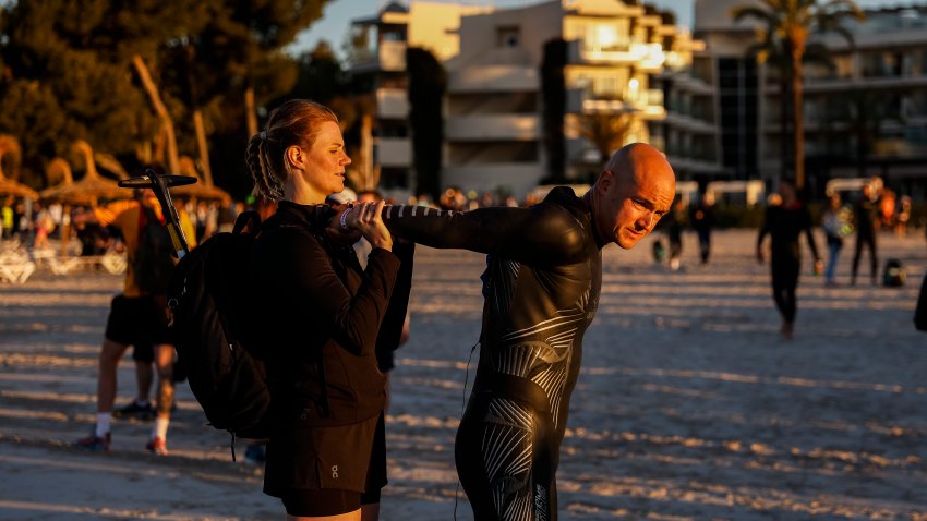 A woman helps an athlete stretch before the start of IRONMAN 70.3 Mallorca on May 11, 2024 in Alcudia, Spain.